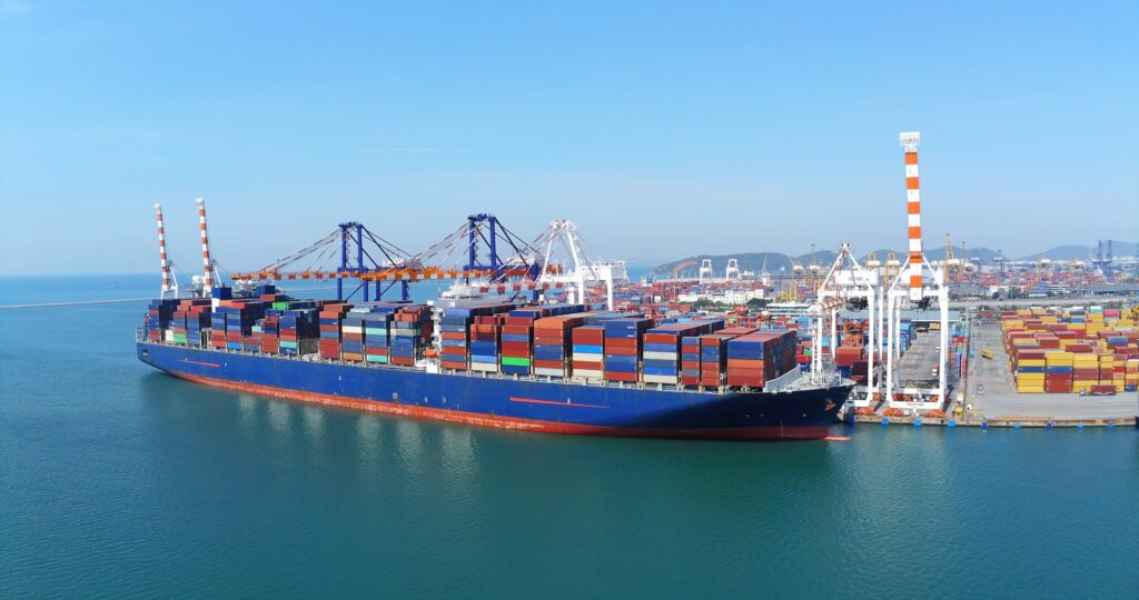 A large container ship is docked at a bustling port, ready for loading and unloading cargo.