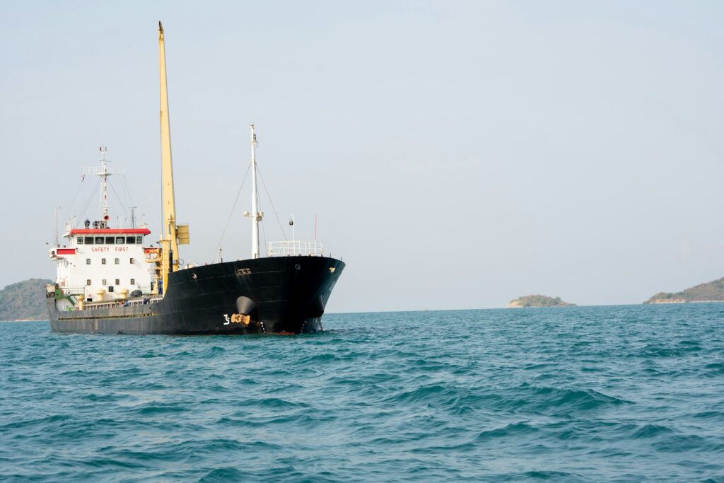 A large boat sailing across the vast ocean under a clear blue sky.