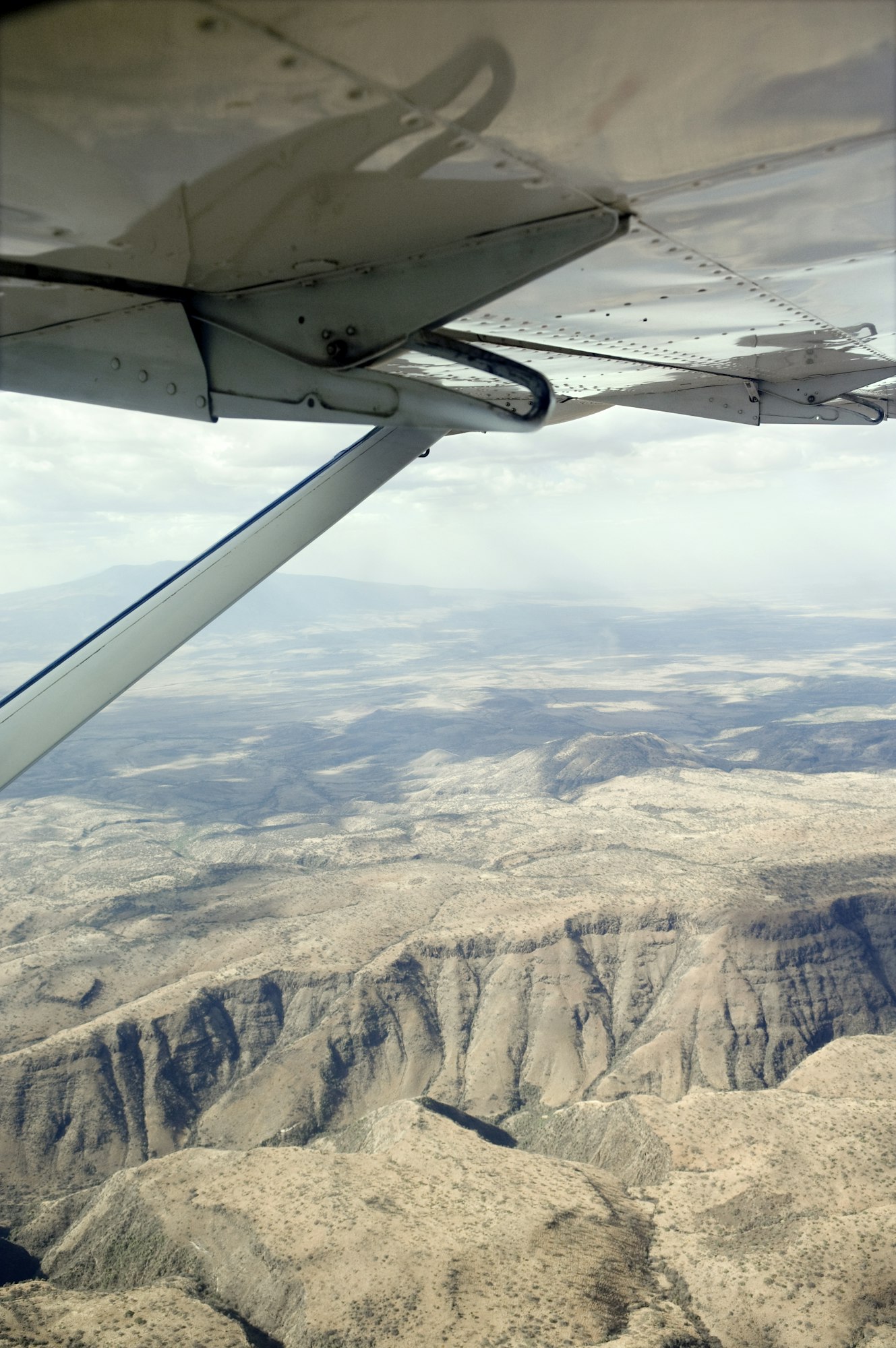 Aerial view of majestic mountains, showcasing their peaks and valleys from the perspective of an airplane window.