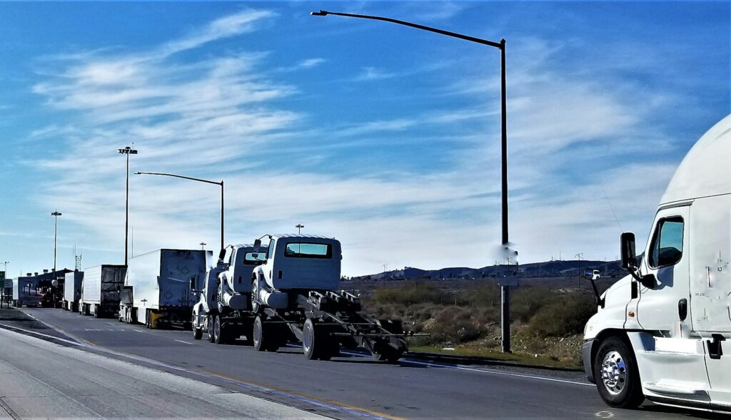 A long line of semi trucks parked on the highway, showcasing a busy transportation route.