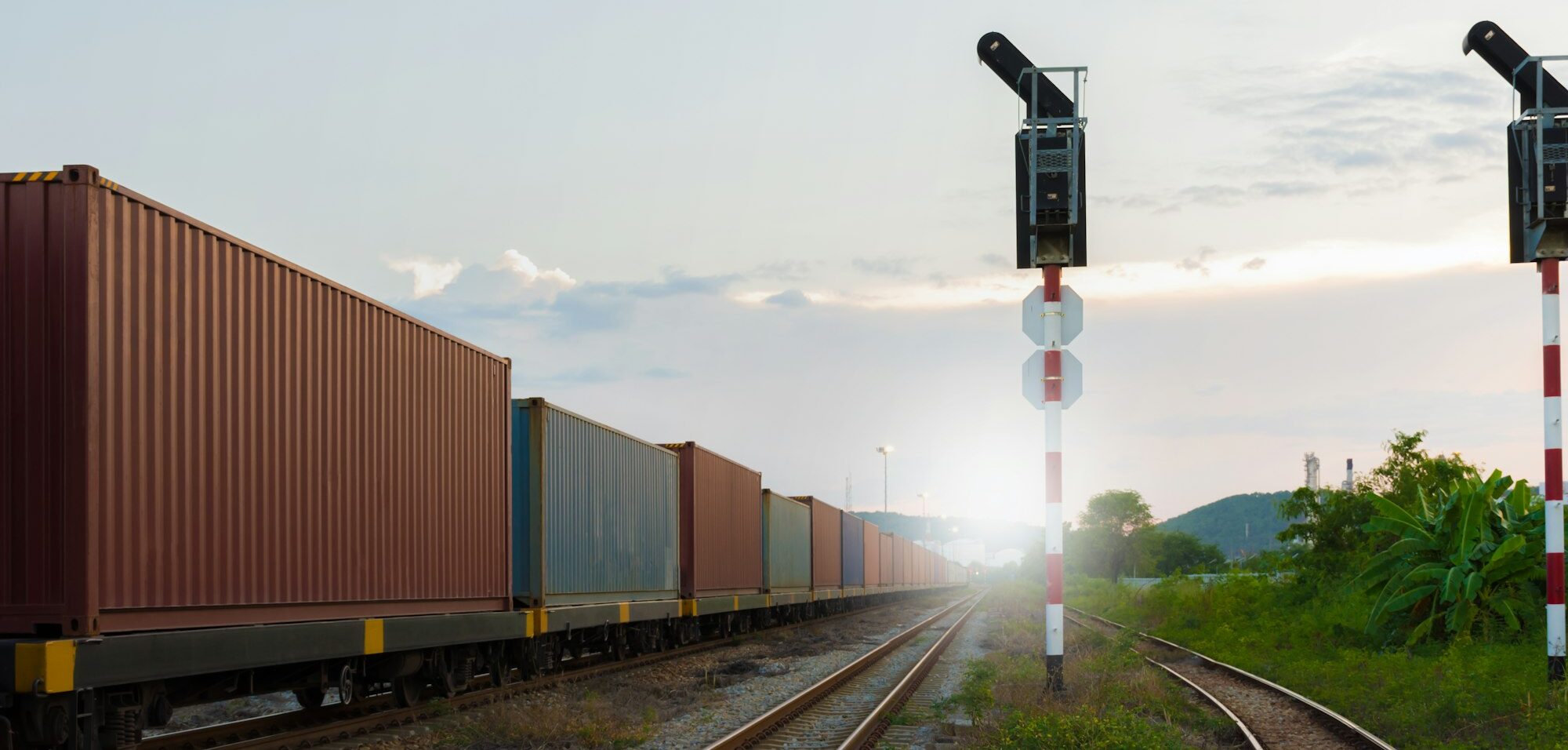 A train moves along the tracks, illuminated by a signal light indicating its path ahead.