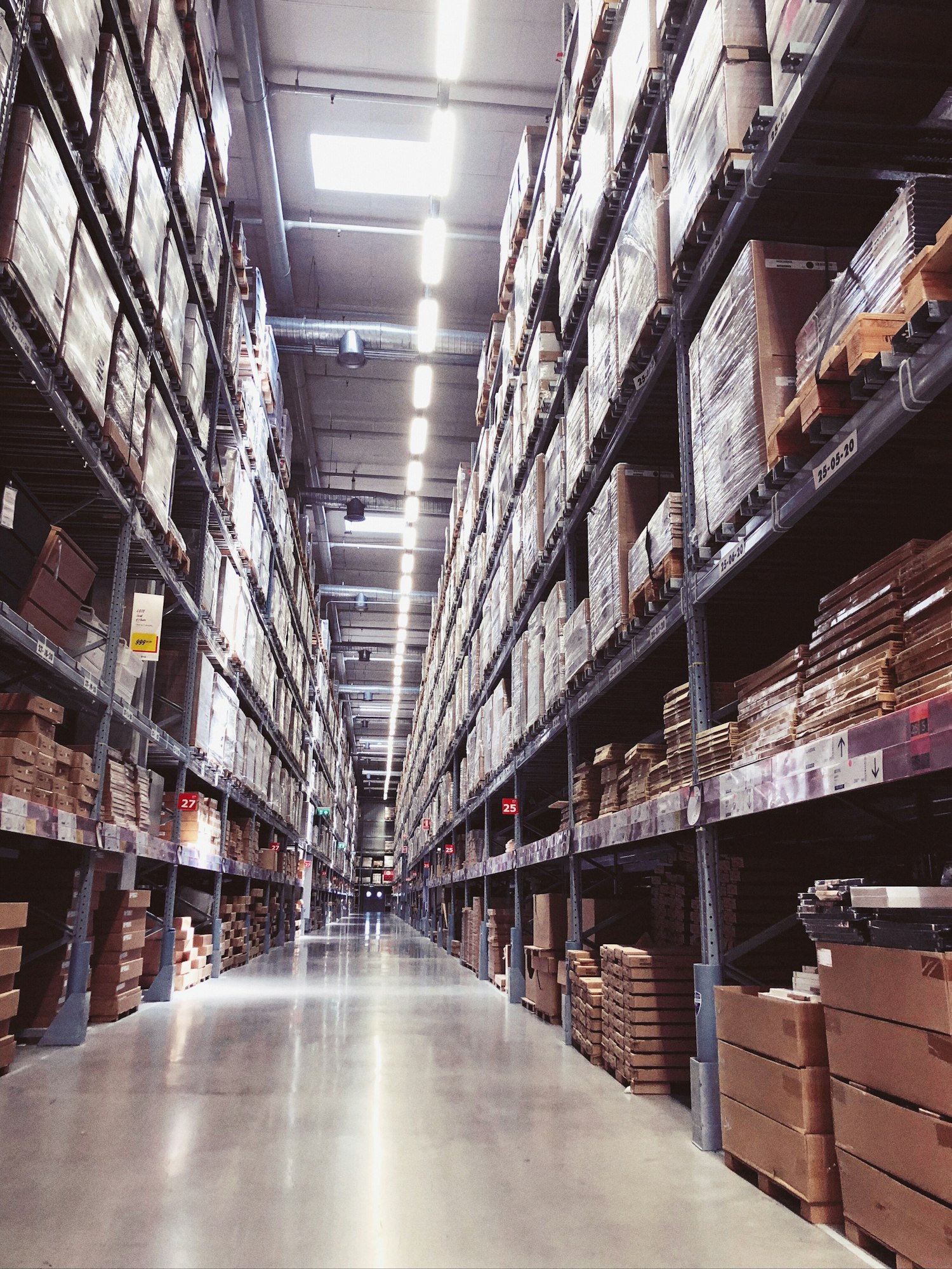 A spacious warehouse aisle filled with stacked boxes and shelves, showcasing organized storage and inventory management